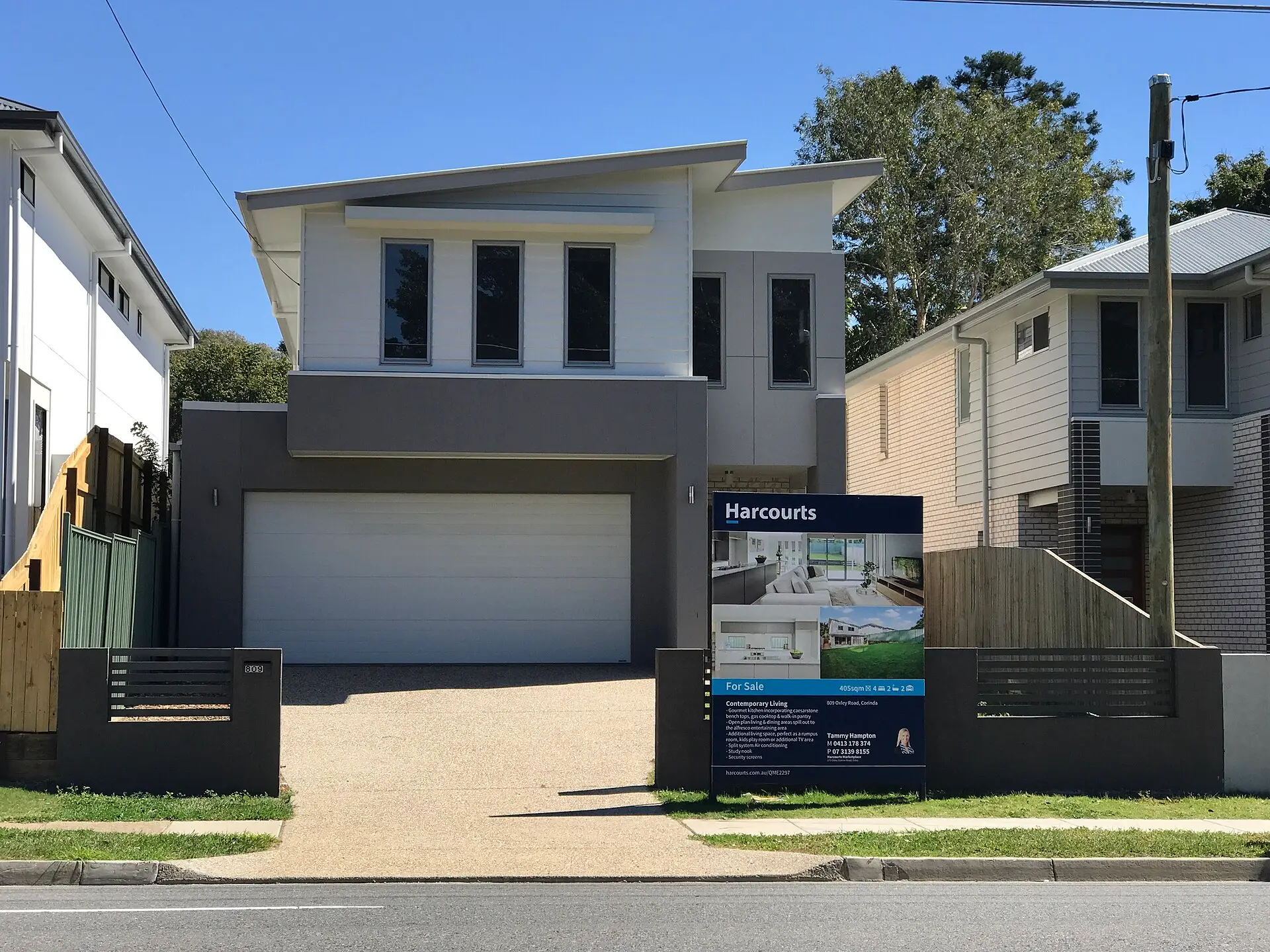 Modern two-storey home with a real estate for sale board on the front fence