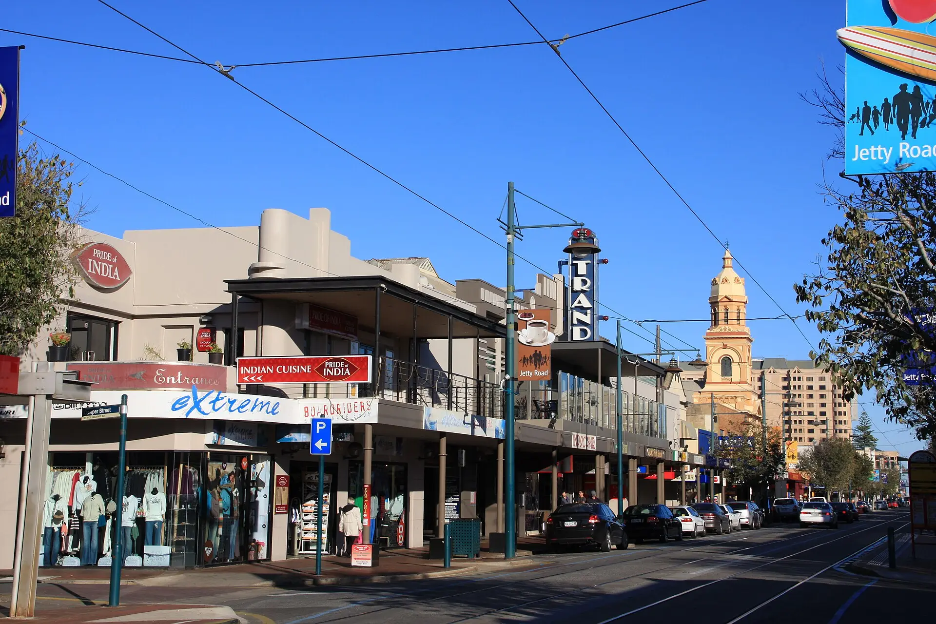 Shops and cafes along Jetty Road, Glenelg, with the tramline and town hall tower