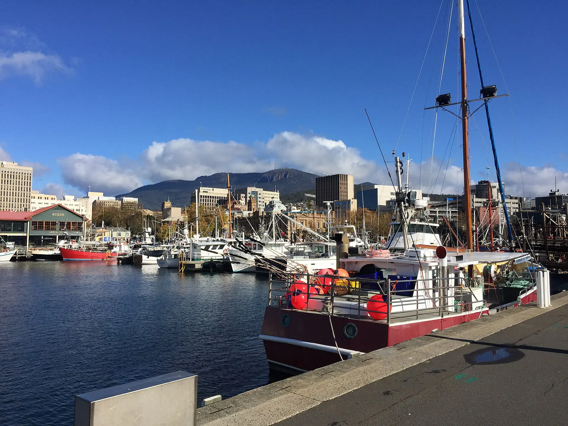 Hobart waterfront with fishing boats moored at the docks and kunanyi Mount Wellington behind