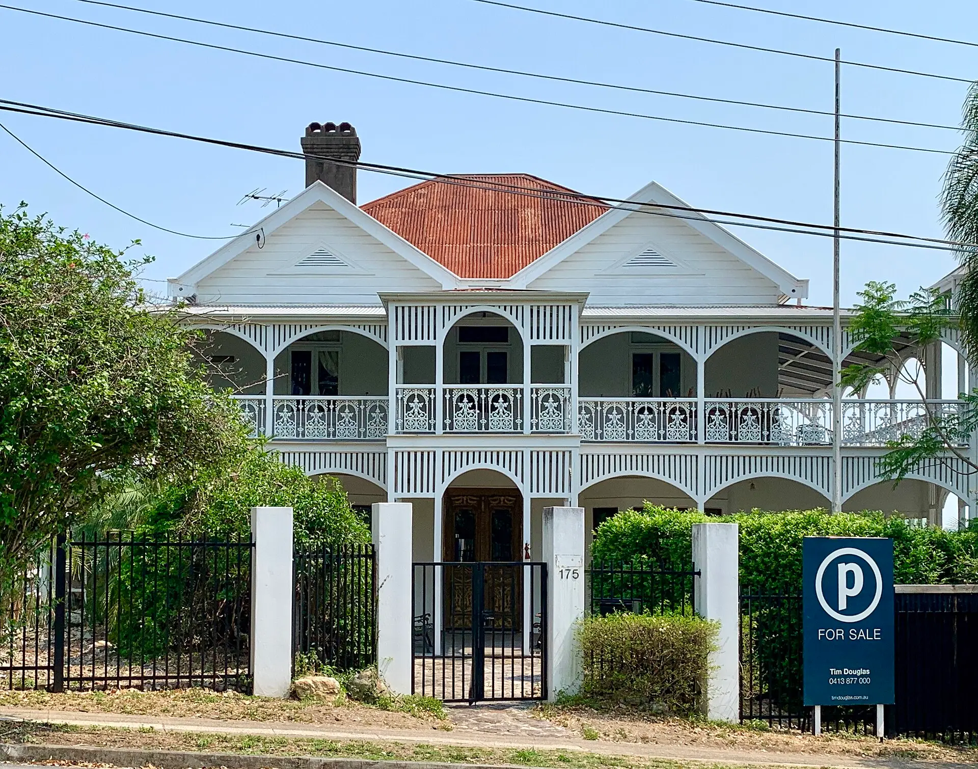 Restored Queenslander home with a for sale sign at the front gate